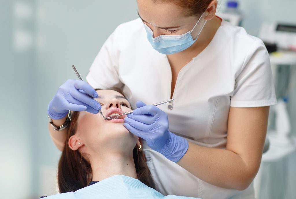 Female hygienist cleaning a young woman's teeth