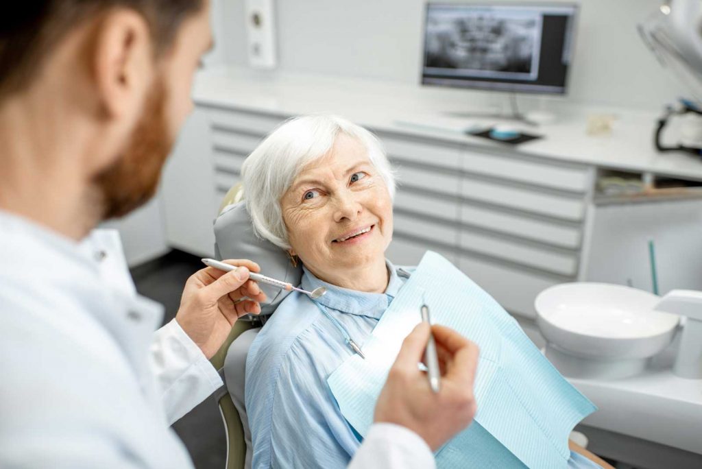Elderly woman smiling at male dentist